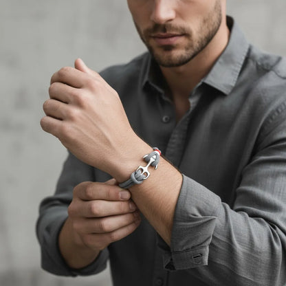 Modelo masculino ajustando a pulseira de corda cinza com detalhe metálico prateado no pulso.
