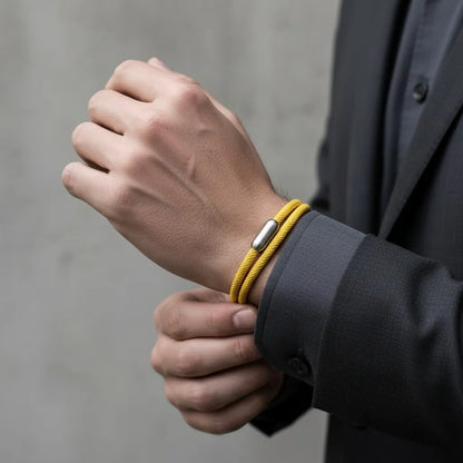 Homem ajustando pulseira masculina de corda amarela com volta dupla e fecho metálico prateado no pulso.