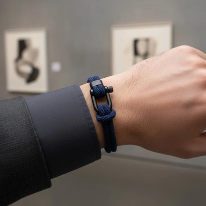 Close no pulso com pulseira masculina de corda azul com fecho preto em ambiente interno minimalista.
