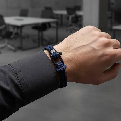 Homem usando pulseira masculina de corda azul com fecho preto em escritório desfocado ao fundo.