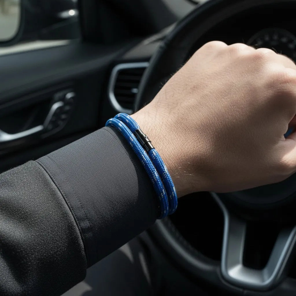 Close de pulseira masculina de corda azul com volta dupla e fecho preto no pulso dentro de um carro.