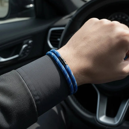 Close de pulseira masculina de corda azul com volta dupla e fecho preto no pulso dentro de um carro.
