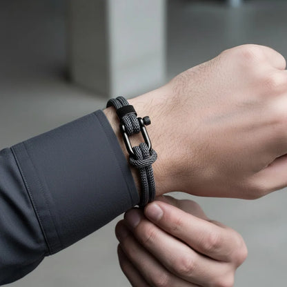 Homem ajustando pulseira masculina de corda cinza com fecho preto e design moderno no pulso.