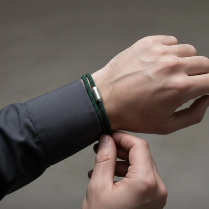 Homem ajustando pulseira masculina de corda verde com volta dupla e fecho metálico prateado no pulso.
