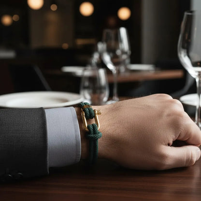 Pulseira masculina de corda verde com fecho dourado no pulso de um homem em um jantar sofisticado.