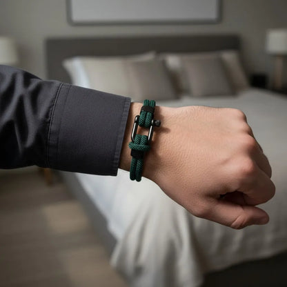 Close de pulseira masculina de corda verde com fecho preto no pulso, com quarto ao fundo.