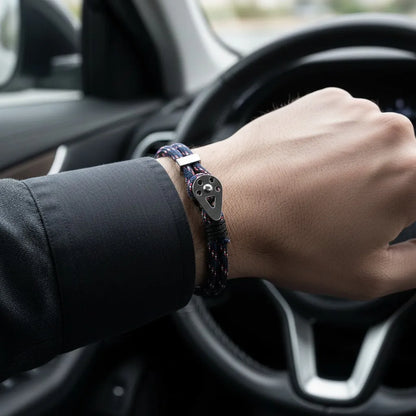 Pulseira masculina de corda azul com detalhe metálico prateado no pulso, fotografada dentro de um carro.
