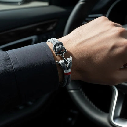 Close no pulso masculino usando pulseira de corda cinza com detalhe metálico prateado dentro de um carro.
