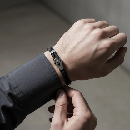 Pulseira de corda preta masculina com placa metálica prateada e design minimalista, ajustada no pulso.