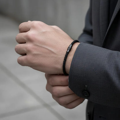 Pulseira masculina de corda preta trançada com fecho metálico, combinada com traje social masculino.
