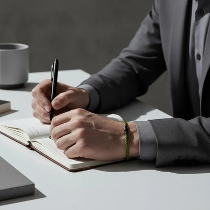 Pulseira masculina de corda verde com fecho preto no pulso de homem escrevendo em um caderno no escritório.