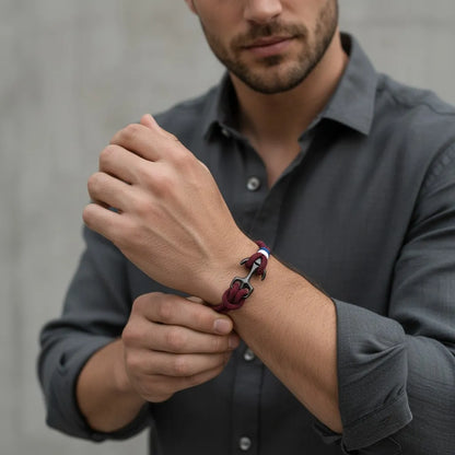 Homem usando pulseira de corda vinho com âncora preta e detalhes em branco e azul no pulso.