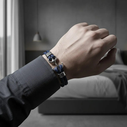 Homem usando pulseira de couro azul com âncora em metal prateado, combinada com camisa social escura em ambiente interno elegante.