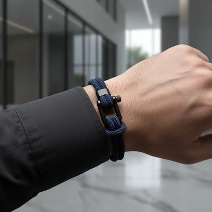 Close no pulso com pulseira masculina de corda azul com fecho preto em ambiente moderno.