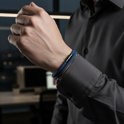 Detalhe de pulseira masculina de corda azul-marinho de volta dupla em ambiente de escritório.