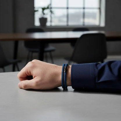 Pulseira masculina de corda azul-marinho com fecho preto no pulso sobre uma mesa de trabalho.