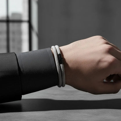 Detalhe de pulseira masculina de corda cinza de volta dupla com fecho metálico preto no pulso.