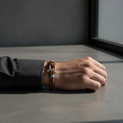 Detalhe de pulseira masculina de corda marrom com fecho metálico prateado no pulso.
