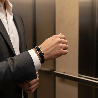 Homem de terno usando pulseira masculina de corda preta com fecho prateado em um elevador.
