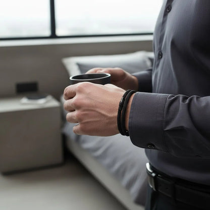 Homem segurando uma caneca e usando pulseira masculina de corda preta.