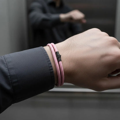 Detalhe de pulseira masculina de corda rosa com fecho preto em ambiente corporativo.