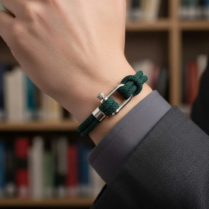 Detalhe de pulseira masculina de corda verde com fecho prateado no pulso em uma biblioteca.