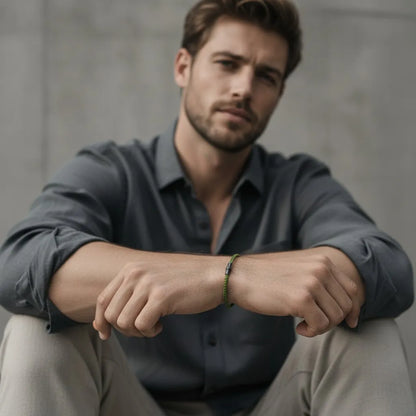 Homem usando pulseira masculina de corda verde fina com fecho metálico preto em um visual casual.