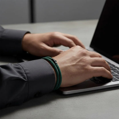 Homem trabalhando no notebook e usando pulseira masculina de corda verde de volta dupla.