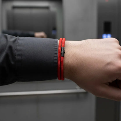 Detalhe de pulseira masculina de corda vermelha de volta dupla em ambiente corporativo.