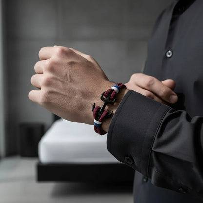 Pulseira masculina de corda vinho com fecho de âncora preta e detalhes em branco e azul, usada no pulso com camisa social.