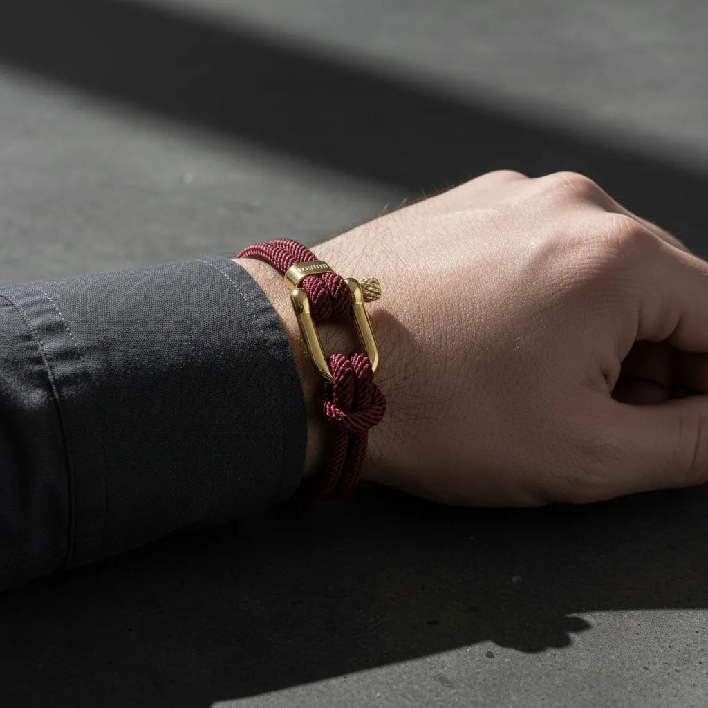 Close da pulseira masculina de corda vinho com fecho dourado no pulso de um homem.