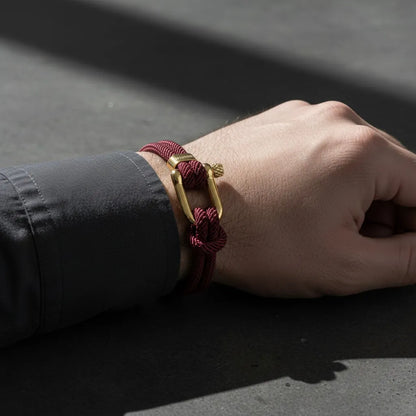 Close da pulseira masculina de corda vinho com fecho dourado no pulso de um homem.