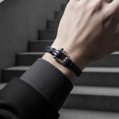 Close da pulseira masculina de couro azul com fecho metálico prateado em ambiente moderno com escada ao fundo.
