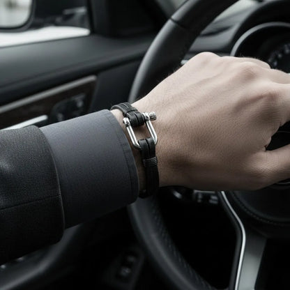 Homem dirigindo enquanto usa pulseira masculina de couro preta com detalhe metálico prateado no pulso.