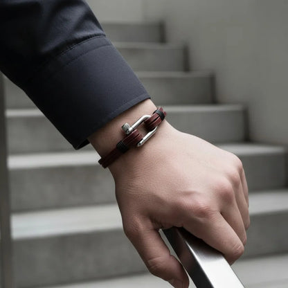 Close da pulseira masculina de couro vinho com fecho metálico prateado em escada de ambiente moderno.