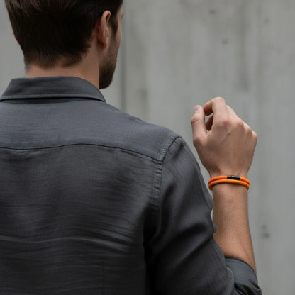 Homem visto de costas usando pulseira masculina de corda laranja com volta dupla em um visual casual e moderno.