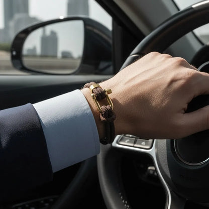 Homem usando pulseira masculina de corda marrom com acabamento dourado enquanto dirige um carro.