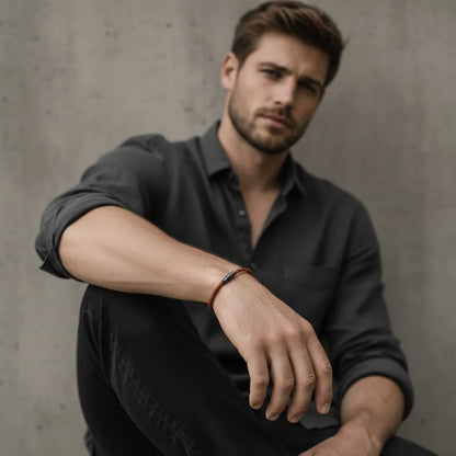 Homem usando pulseira masculina de corda marrom fina com fecho preto em um visual casual.