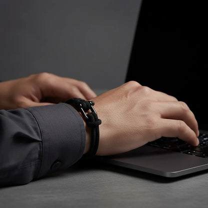 Homem digitando no notebook enquanto usa pulseira masculina de corda preta com fecho preto.